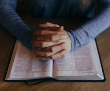 folded hands on bible